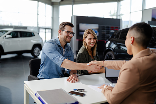 A couple finalize the purchase of a new car they financed with a credit union auto loan.