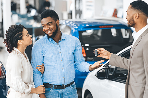A happy couple receive the keys to the new car they financed with a credit union auto loan.
