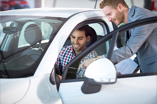 A man talks to a salesman about a new car he is financing with a credit union auto loan.