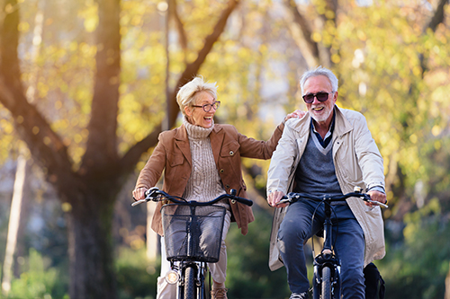 Retired couple enjoying a bike ride together, embracing their active lifestyle thanks to the security of their retirement savings.